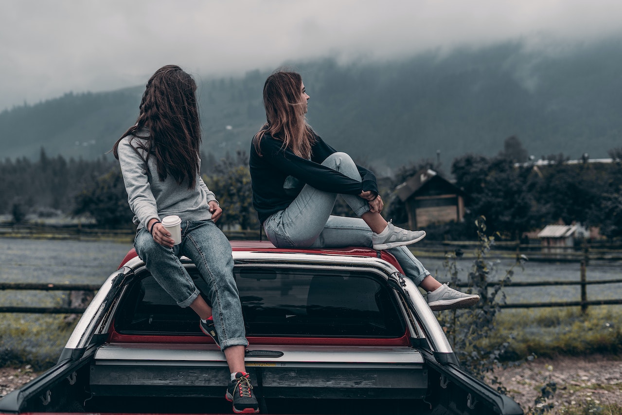 Two women are traveling by their car